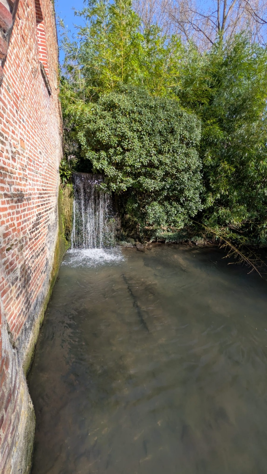 Cascade naturelle le long du mur du moulin, symbole de l'eau qui libère
